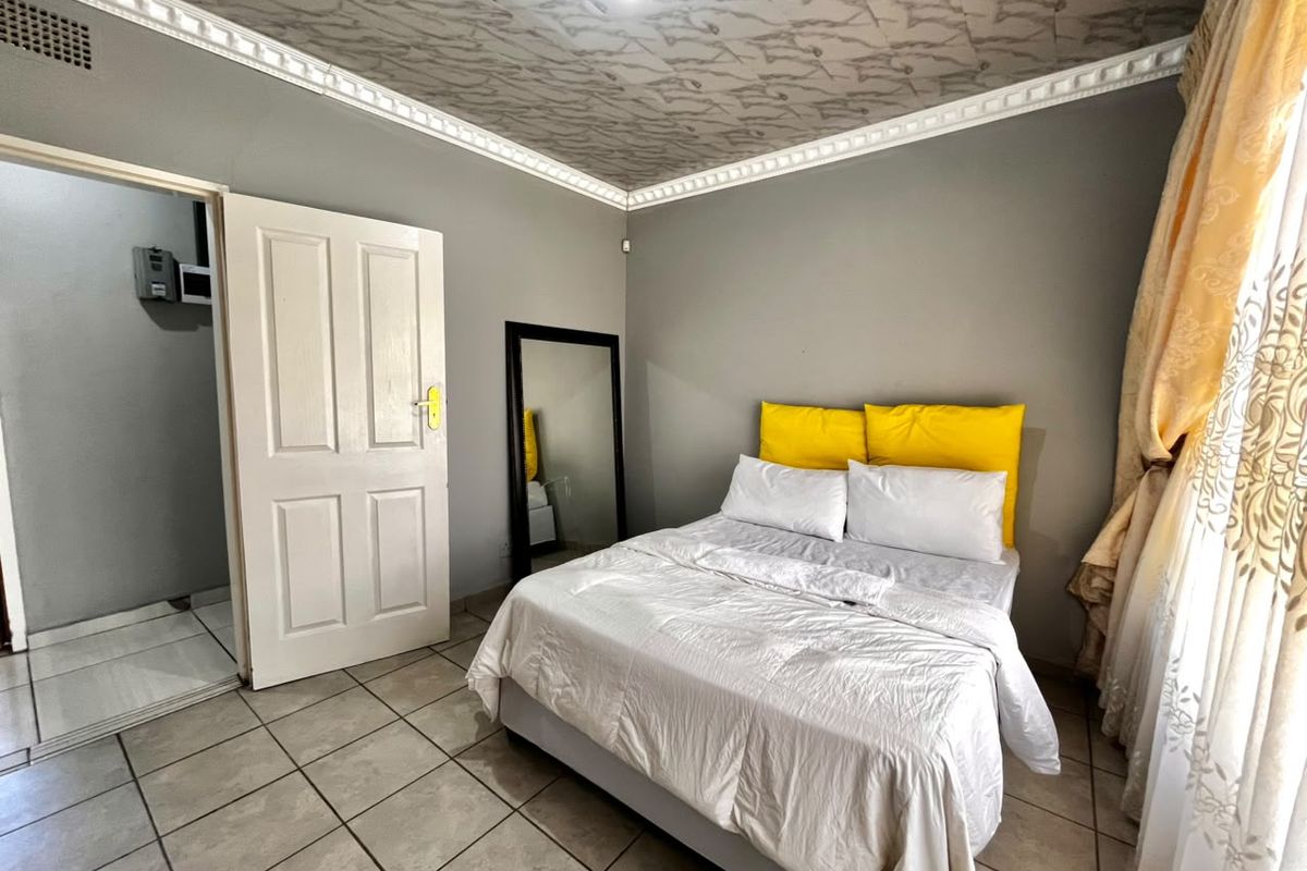 A bedroom featuring tiled flooring, decorative ceiling molding, and a patterned ceiling finish, providing a functional space with neutral wall tones.