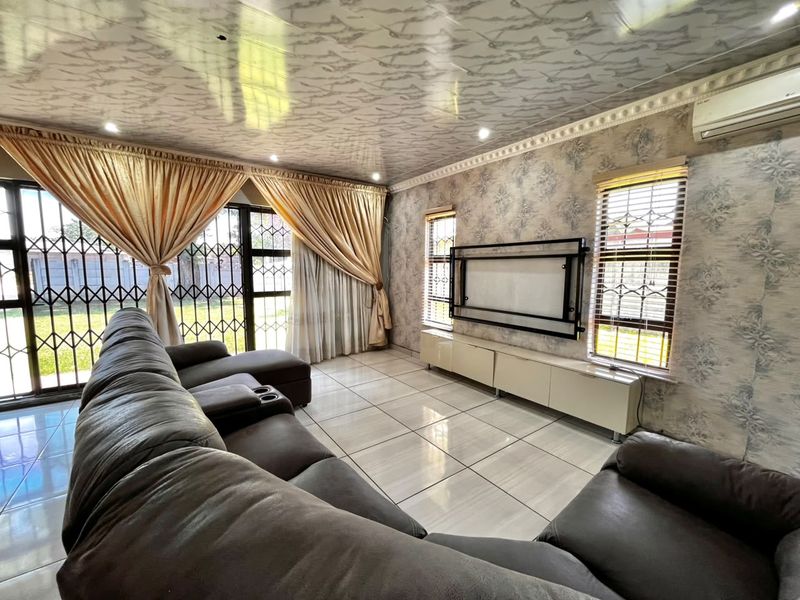 Spacious living room featuring tiled floors, recessed lighting, wall-mounted air conditioning, and a built-in media console with direct access to the garden.