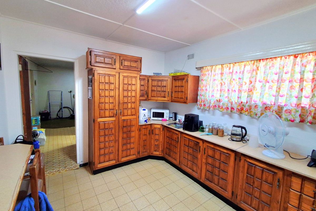 A functional kitchen featuring traditional wooden cabinetry, laminate countertops, and tiled flooring, offering a dated aesthetic ready for modernization.