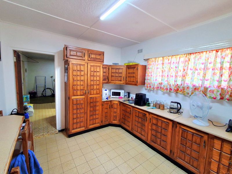 A functional kitchen featuring traditional wooden cabinetry, laminate countertops, and tiled flooring, offering a dated aesthetic ready for modernization.