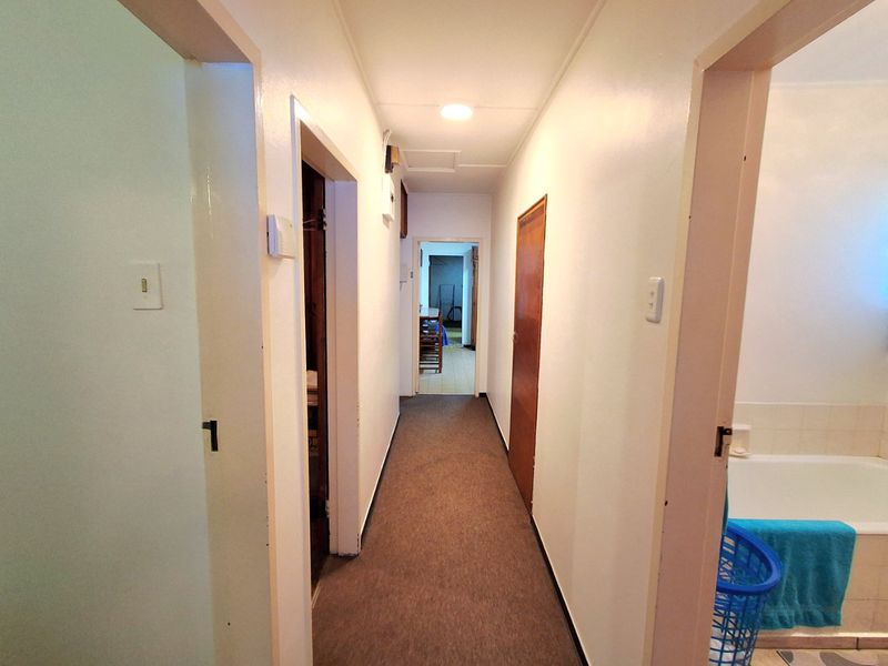 A functional hallway connecting multiple rooms, featuring neutral wall finishes, carpeted flooring, and standard internal doors.