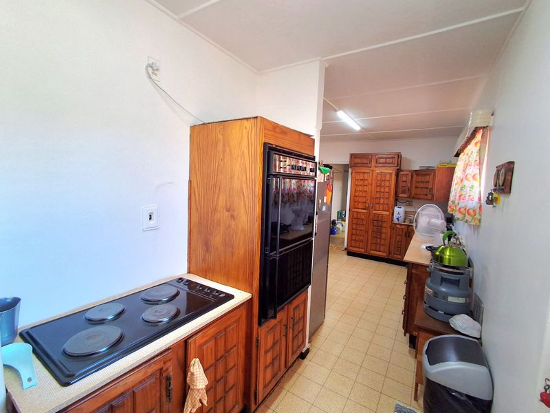 A dated kitchen featuring traditional wooden cabinetry, a built-in oven, and an electric hob, offering significant potential for a modern renovation.