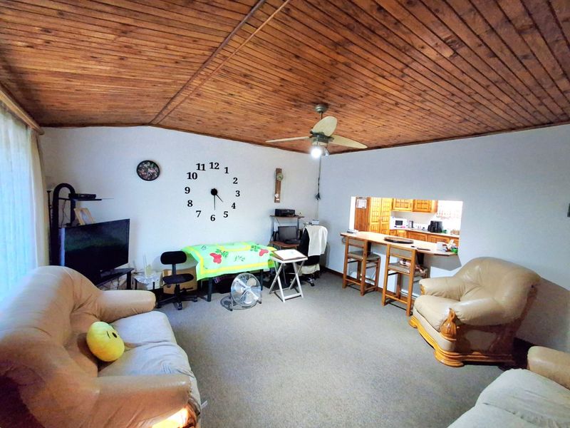Open-plan living area featuring a distinctive timber-clad vaulted ceiling, ceiling fan, and a convenient breakfast bar pass-through connecting to the kitchen.