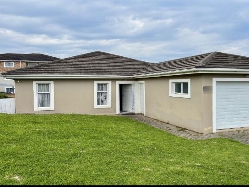 Front elevation of a single-story townhouse featuring a tiled roof, integrated single garage, and a paved driveway with surrounding lawn.