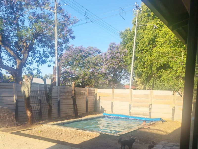 Outdoor pool area featuring a swimming pool and precast concrete boundary wall, offering potential for landscaping and garden improvement.