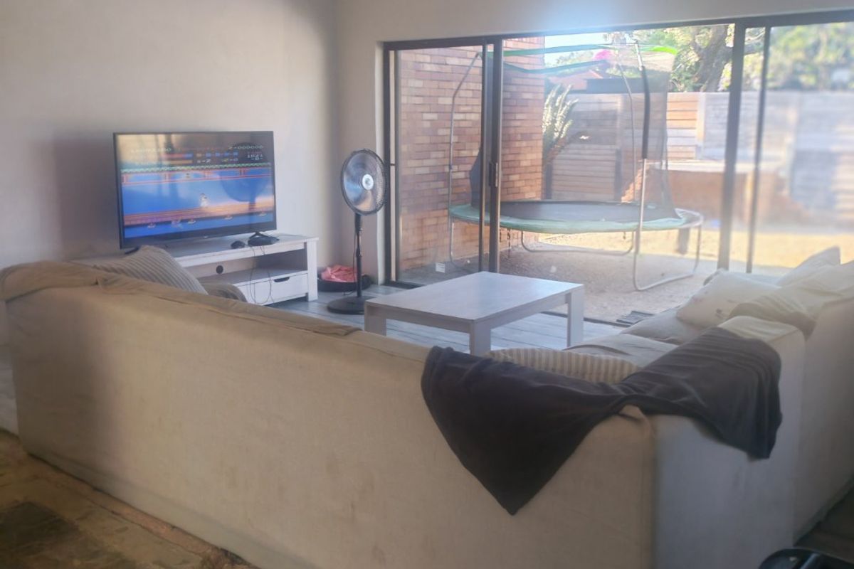 Living room featuring large sliding glass doors leading to the rear garden, with recessed lighting and unfinished flooring requiring completion.