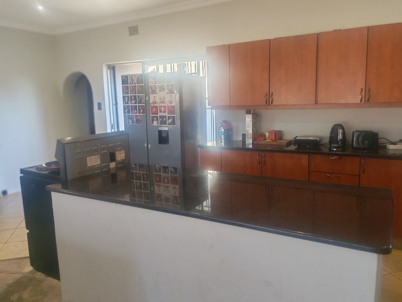 A functional kitchen featuring wooden cabinetry, dark granite countertops, and a central island, providing ample workspace and storage.