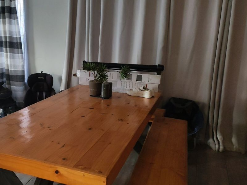 A dining area featuring tiled flooring and neutral curtains, providing a functional space for meals.