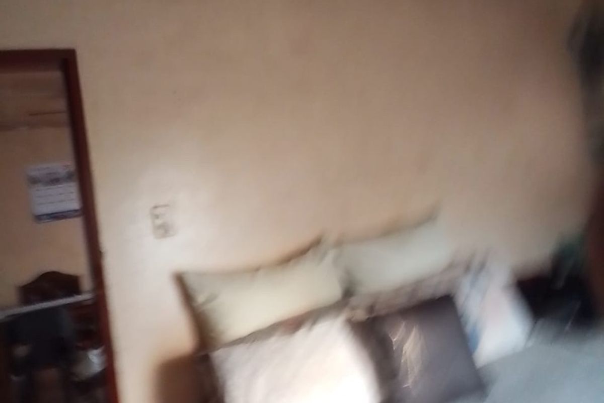 A bedroom interior view showing a bed and a doorway leading to an adjacent room.