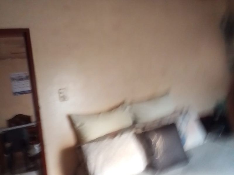 A bedroom interior view showing a bed and a doorway leading to an adjacent room.