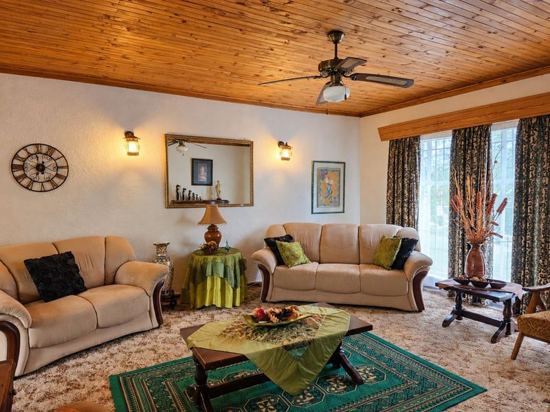 A cozy living room featuring a warm timber tongue and groove ceiling, ceiling fan, and sliding glass door access to the exterior.