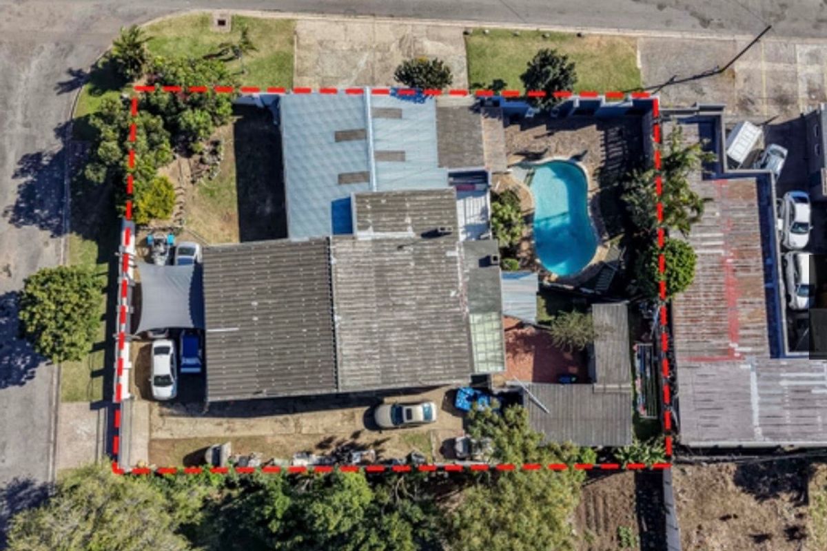 Aerial view of the property showing the house layout, swimming pool, driveway, and surrounding garden area within the marked boundary.