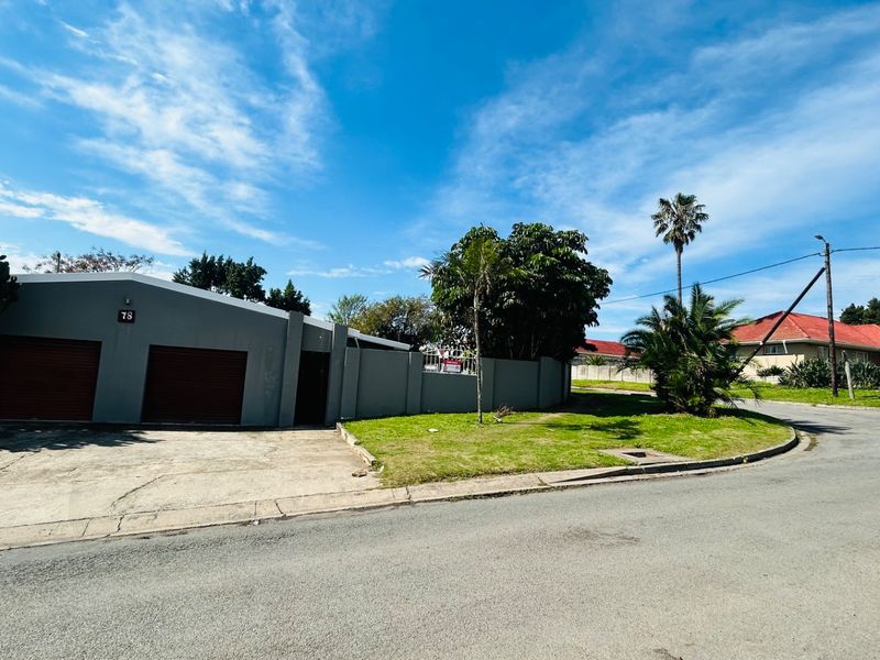 Street view of the property featuring a double garage with roller doors, a concrete driveway, and a perimeter wall on a corner lot.