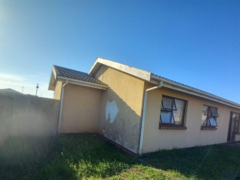 Rear view of the house showing exterior walls with visible paint peeling and plaster damage, tiled roof, and surrounding boundary wall.