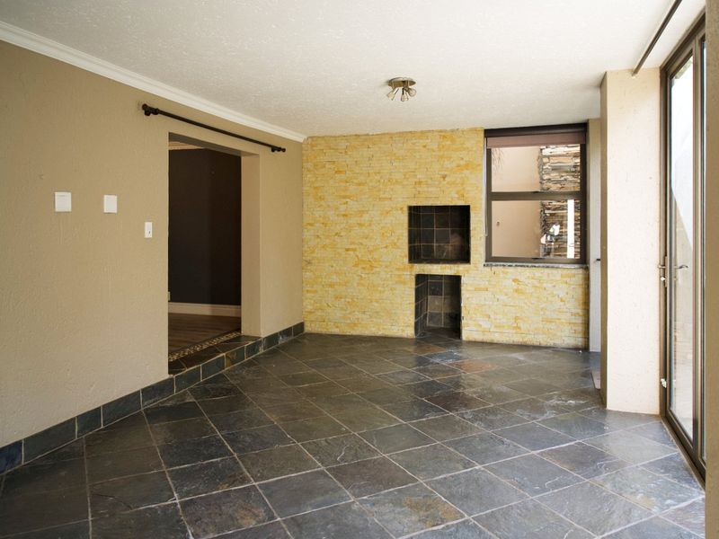 Covered patio area featuring slate tile flooring, a built-in braai with stone cladding, and large sliding glass doors providing access to the exterior.