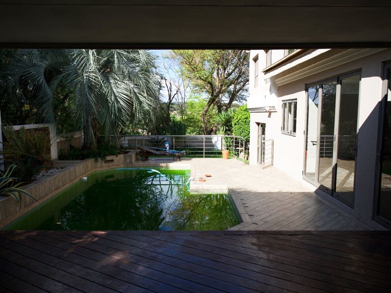 Outdoor pool area featuring a tiled patio, metal railings, and direct access to the home through large sliding glass doors.
