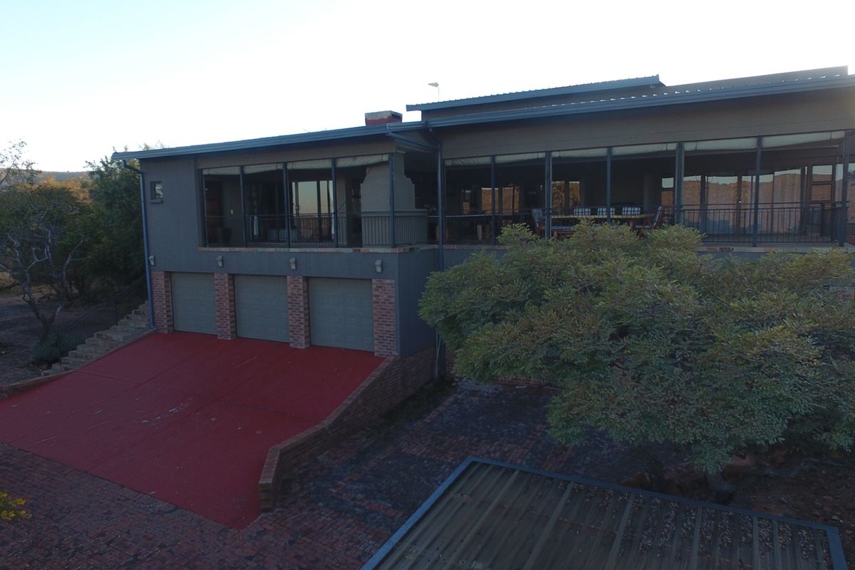 Rear view of a multi-level house featuring a triple garage, a large covered patio area, and a paved driveway.