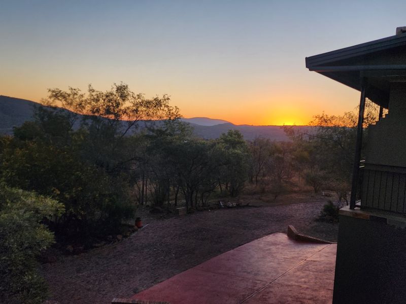 A scenic sunset view overlooking the natural landscape and surrounding hills from the property's elevated patio area.