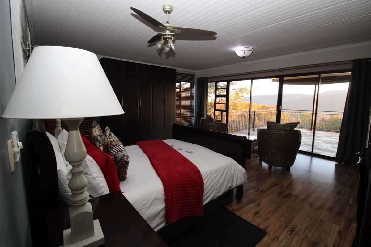 Spacious bedroom featuring laminate flooring, built-in cupboards, and large sliding glass doors that open onto a balcony with scenic views.