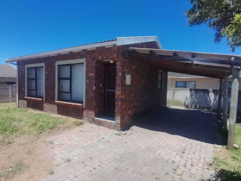 A single-story face brick house featuring a paved driveway, an attached carport, and secure entrance gate, set on a manageable residential plot.