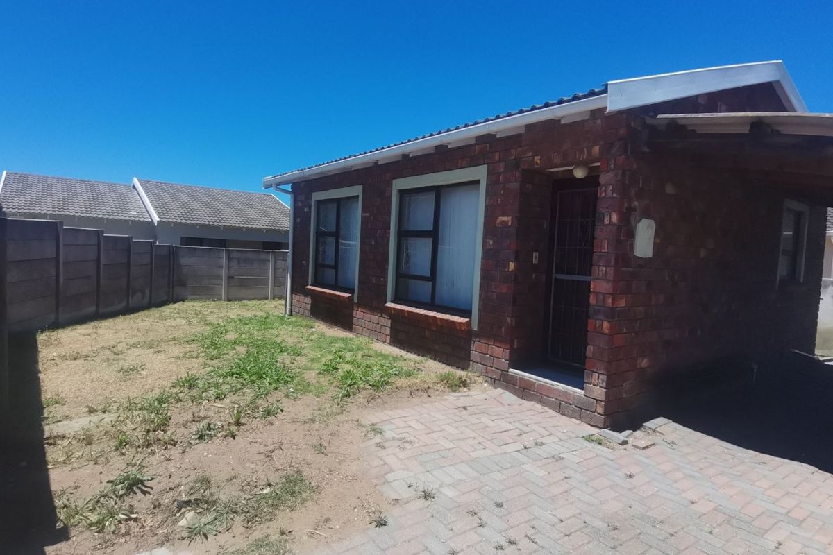 Rear view of a face brick house featuring a paved patio area and a private garden enclosed by precast concrete boundary walls.