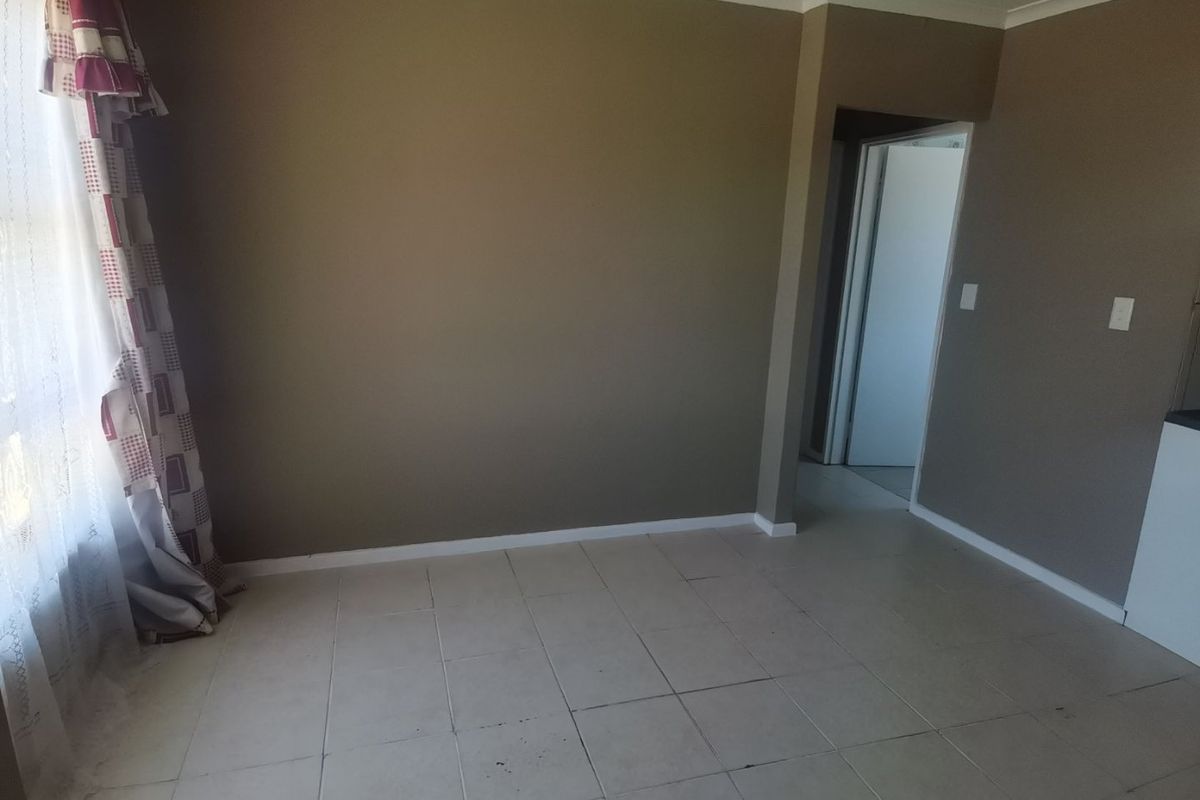 An empty living room featuring neutral wall paint and tiled flooring, providing a blank canvas for interior design updates.