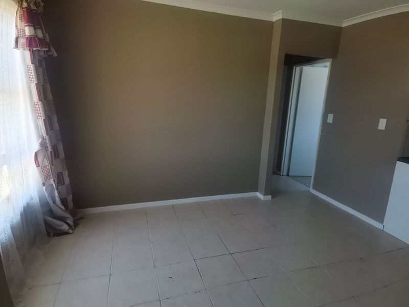 An empty living room featuring neutral wall paint and tiled flooring, providing a blank canvas for interior design updates.