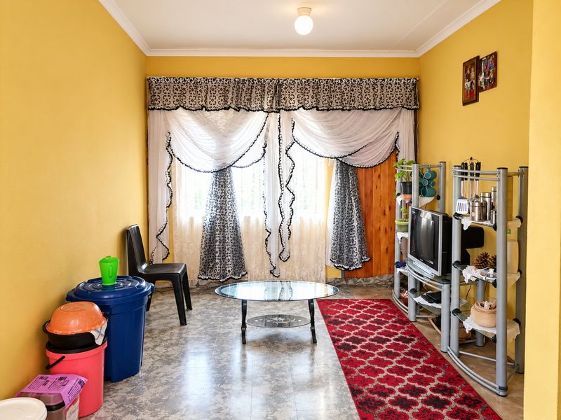 A living room featuring yellow walls, coved ceilings, and vinyl flooring, providing a functional space ready for modern updates and personal styling.