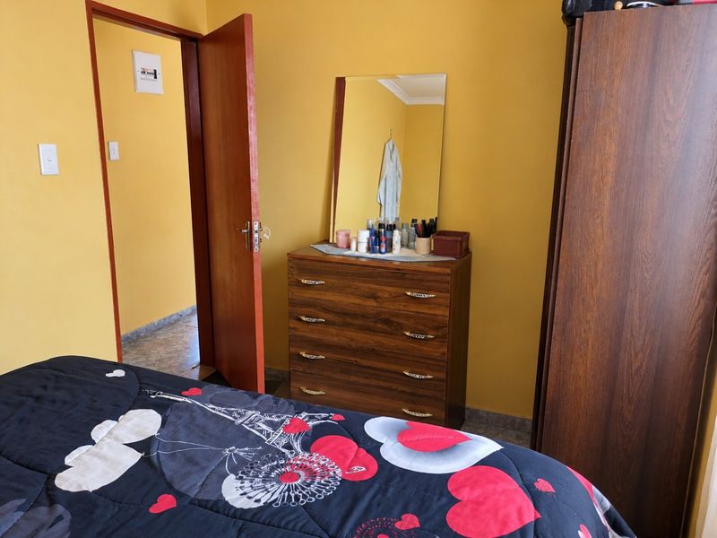 A bedroom featuring yellow painted walls, a wooden door, and an accessible electrical distribution board.