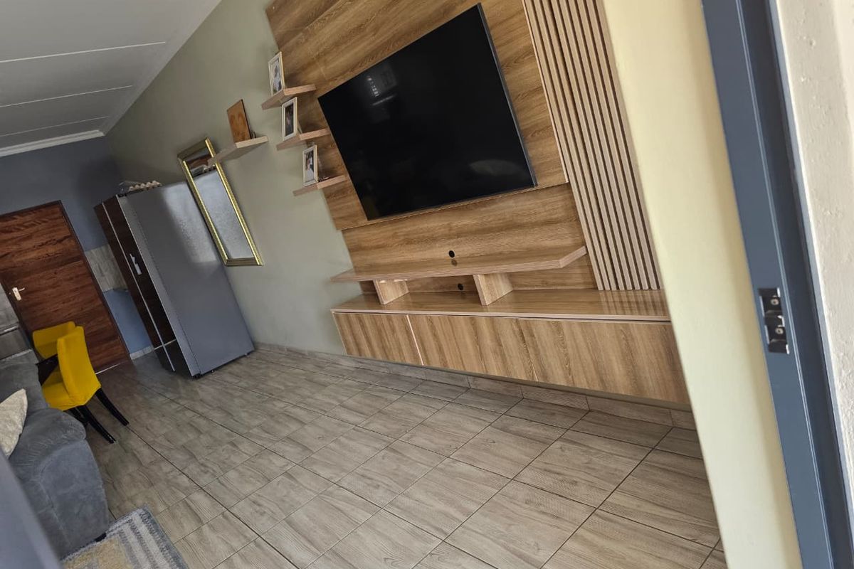A modern living room featuring a custom built-in media unit with slatted wood wall paneling and durable tiled flooring.