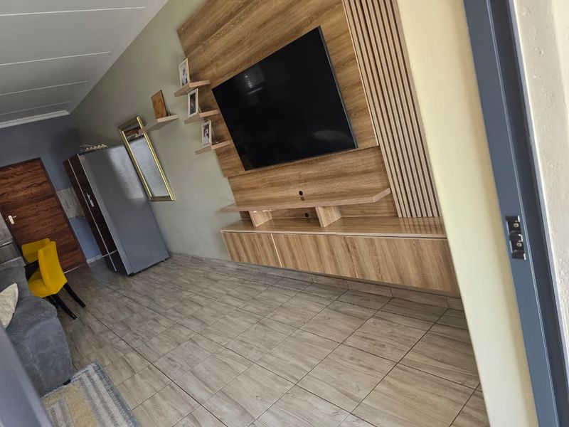 A modern living room featuring a custom built-in media unit with slatted wood wall paneling and durable tiled flooring.