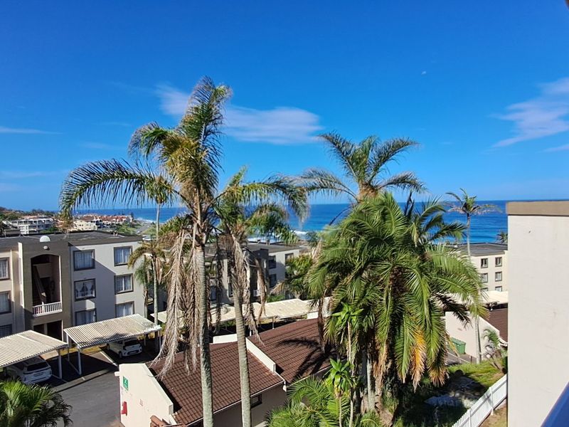 A scenic elevated view overlooking the apartment complex grounds, surrounding neighborhood, and the distant ocean coastline.