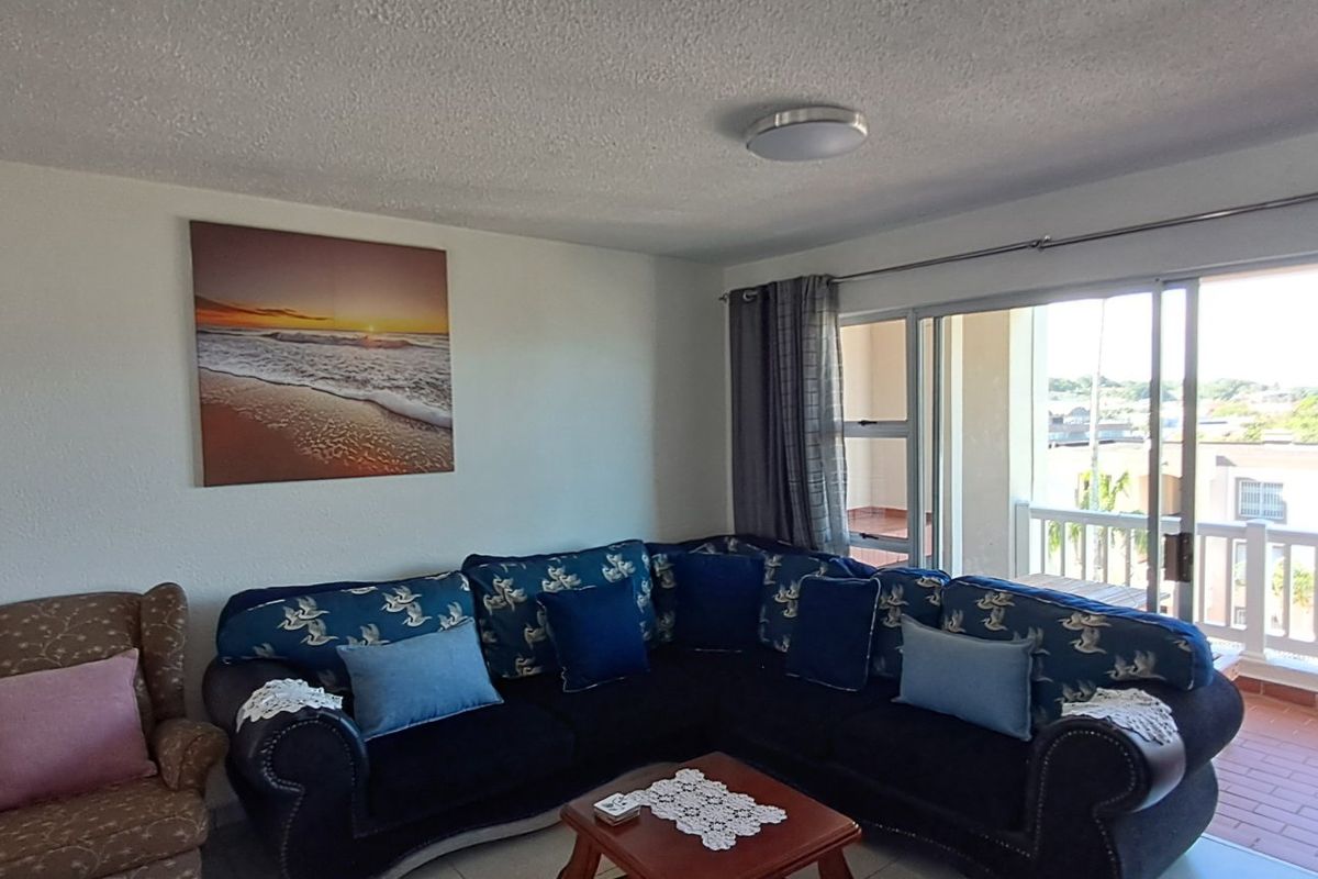 A living room featuring tiled flooring and a large sliding glass door that provides access to an outdoor balcony area.
