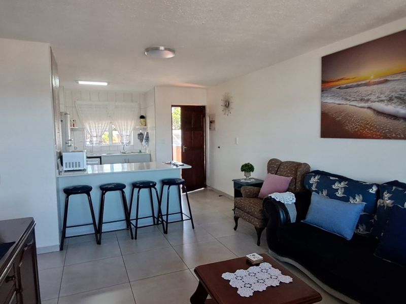 Open plan living area featuring a kitchen with a breakfast bar and tiled flooring throughout, creating a functional and connected living space.
