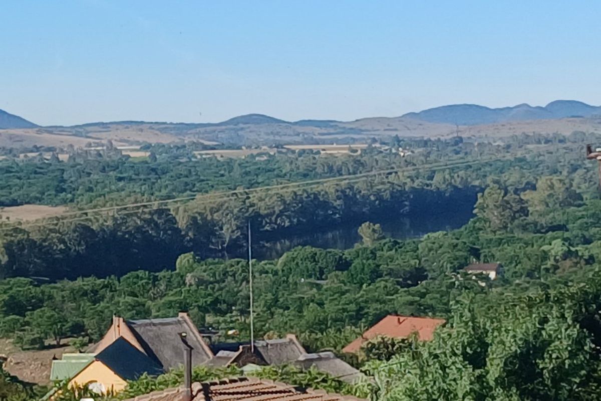 A scenic elevated view overlooking lush green landscape, river, and distant rolling hills.