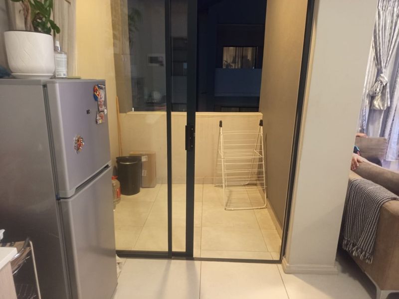 A compact balcony area accessible via a sliding glass door, featuring tiled flooring and a solid perimeter wall.