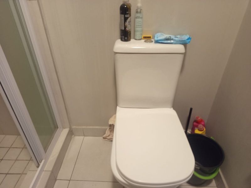 A functional bathroom featuring a standard toilet and a shower enclosure with tiled flooring.