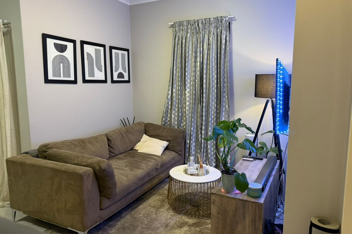 A compact living room area featuring neutral wall finishes and window treatments.
