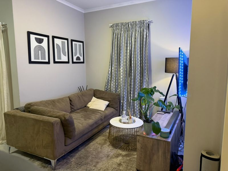 A compact living room area featuring neutral wall finishes and window treatments.