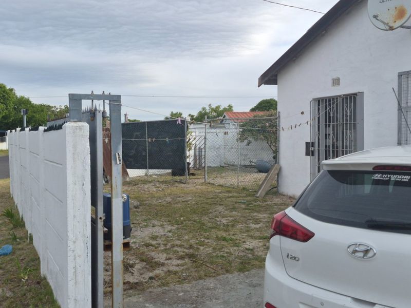 Front exterior view of the property featuring a precast concrete boundary wall, security gate, and security bars on windows.