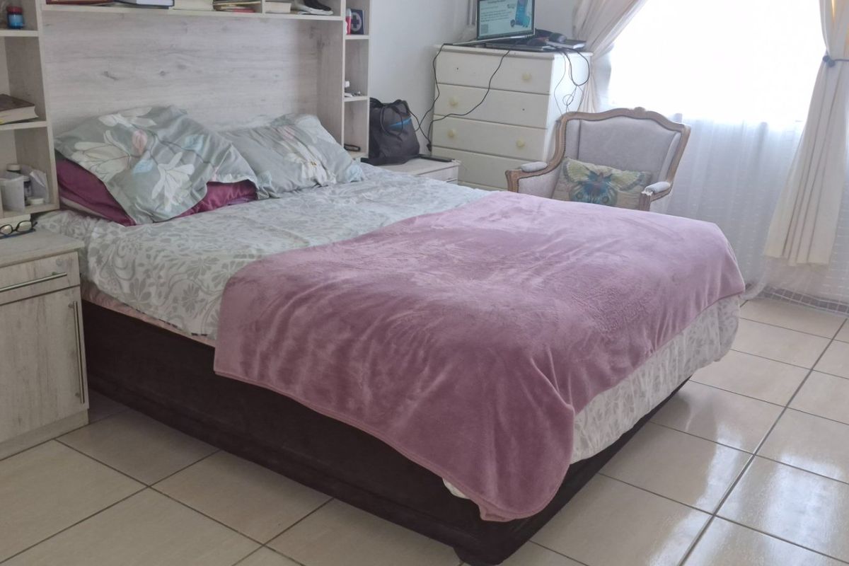 A bedroom featuring tiled flooring and a built-in headboard with integrated shelving units.