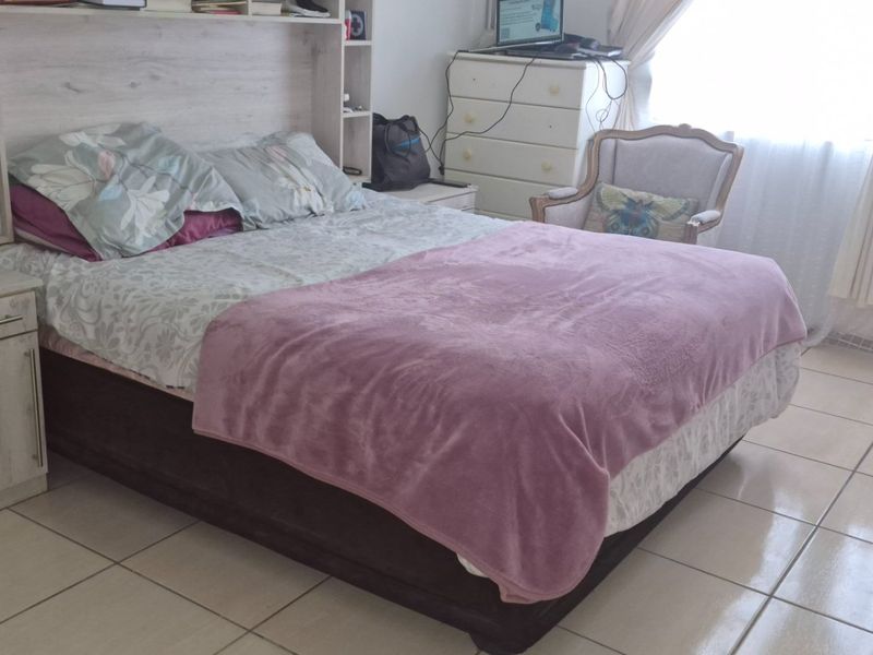 A bedroom featuring tiled flooring and a built-in headboard with integrated shelving units.