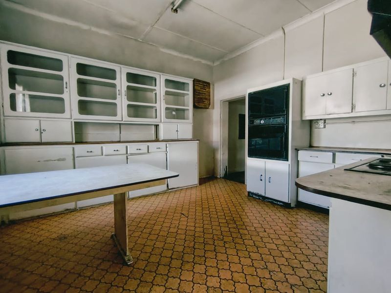 A dated kitchen featuring original built-in cabinetry, a built-in oven, and patterned tile flooring, offering significant potential for a modern renovation.