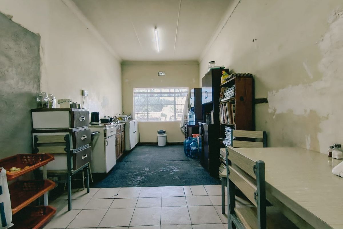 A dated kitchen space featuring built-in cabinetry and tiled flooring, currently requiring significant cosmetic updates and wall repairs.