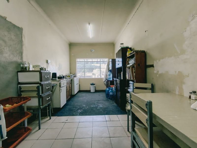 A dated kitchen space featuring built-in cabinetry and tiled flooring, currently requiring significant cosmetic updates and wall repairs.