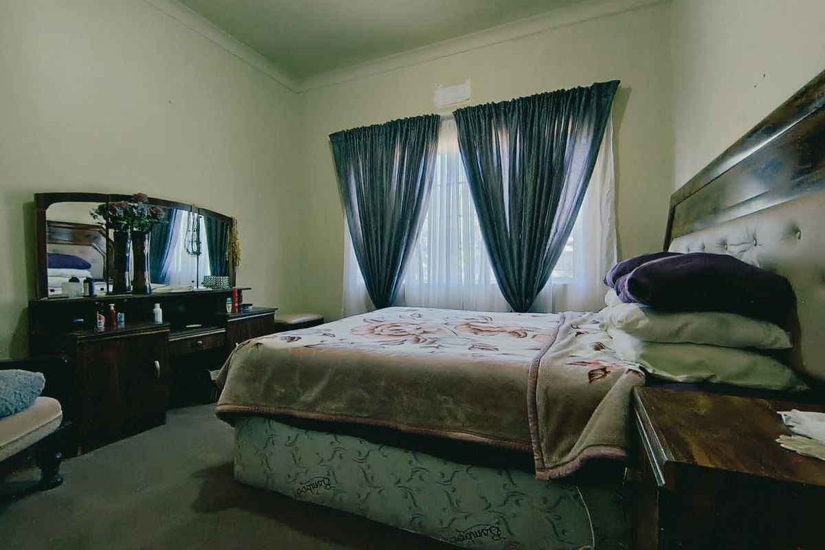 A standard bedroom featuring neutral wall finishes, cove cornicing, and window treatments.