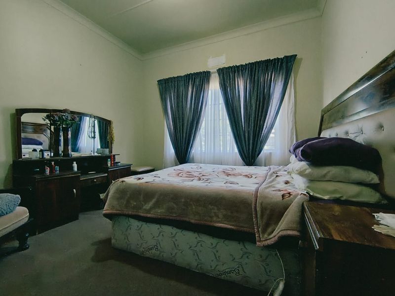 A standard bedroom featuring neutral wall finishes, cove cornicing, and window treatments.