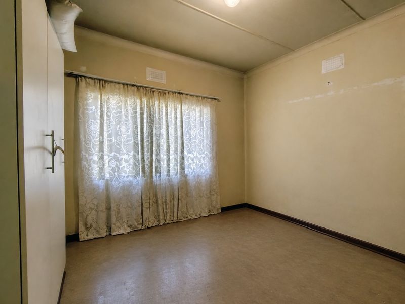 An empty bedroom featuring a built-in wardrobe, ceiling vents, and neutral wall finishes, offering a blank canvas for renovation or restyling.