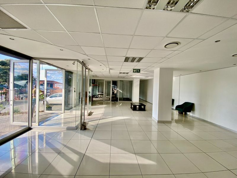 Spacious industrial entry area featuring tiled flooring, a suspended ceiling with recessed lighting, and large glass doors providing ample natural light.