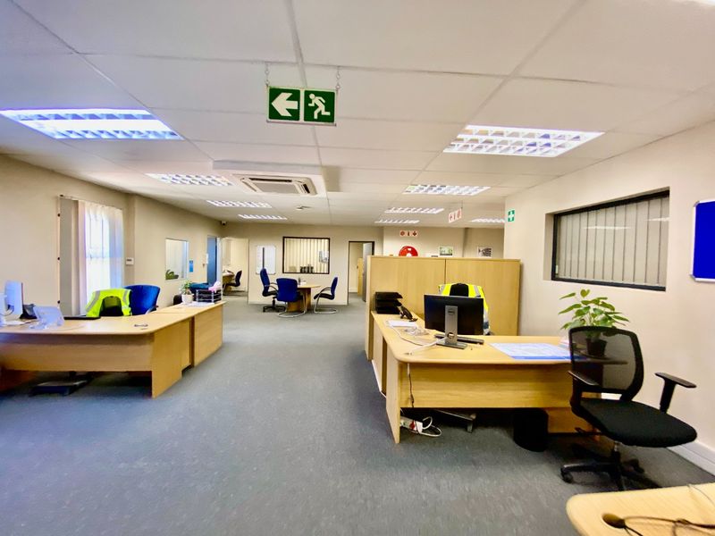Open-plan industrial office space featuring suspended ceilings, recessed lighting, ducted air conditioning, and carpeted flooring with integrated partition walls.